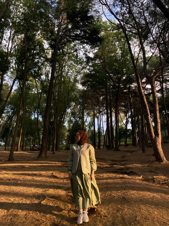 a woman wearing green is walking through the woods