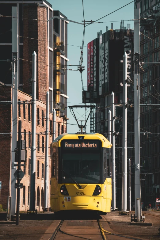 a yellow commuter train on railroad tracks in a city