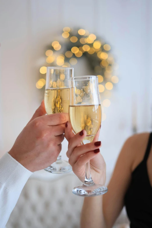 two people holding wine glasses together and toasting with bubbles