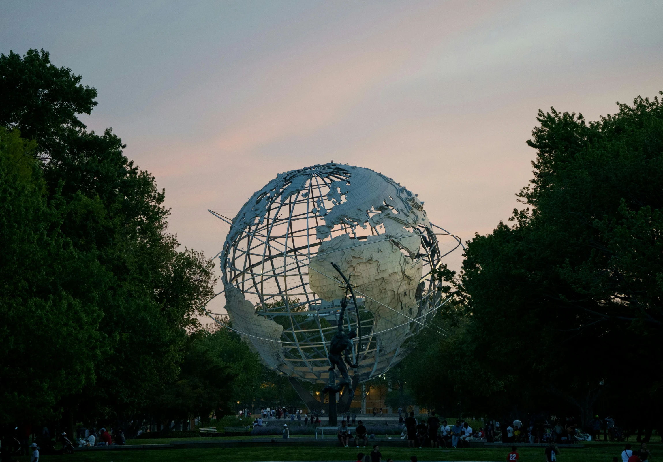 the earth globe at dusk with people in the park around