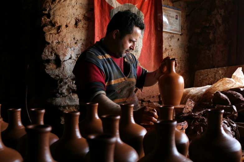 a man is working with some pottery and looking at it