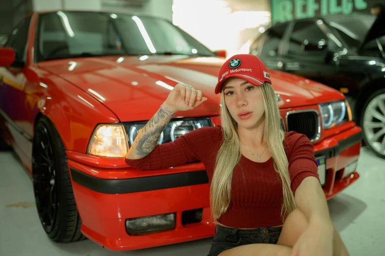 a woman in a hat and red shirt sitting next to cars