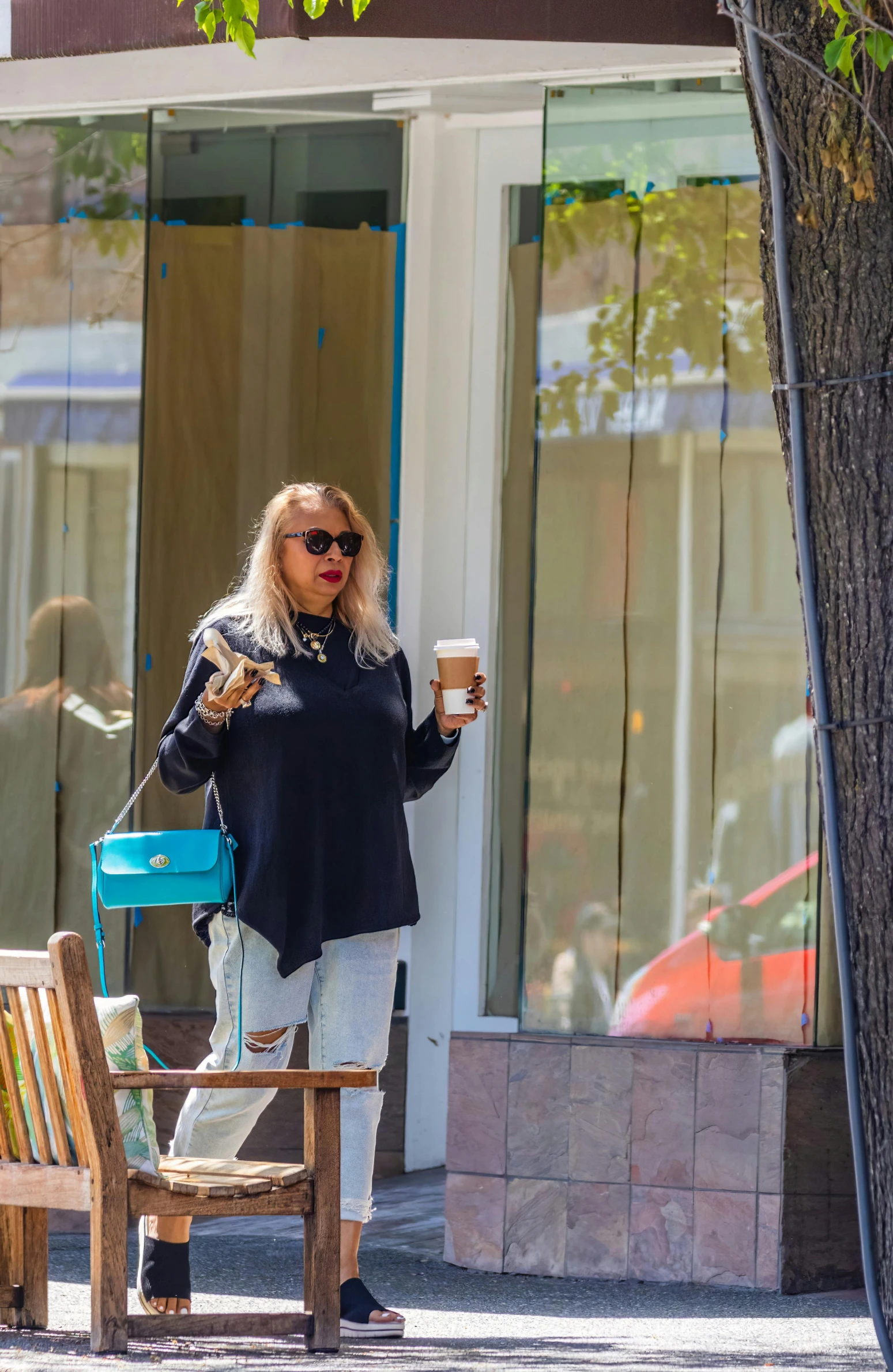 blonde female in all black with her coffee and purse