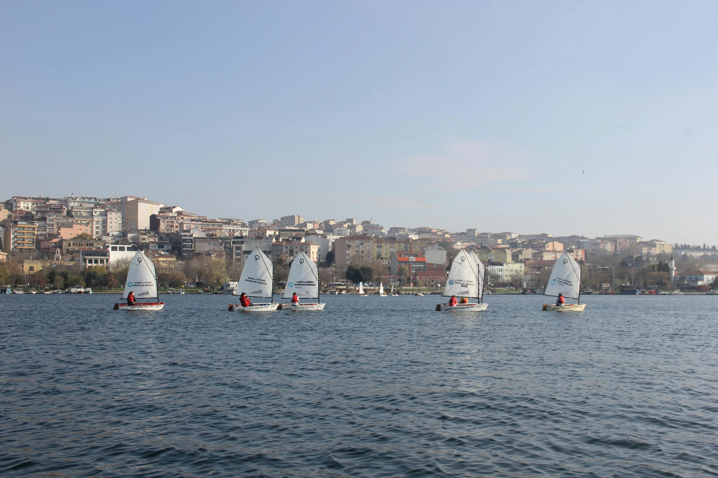 four sailboats sailing in the water near buildings