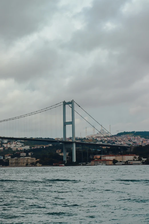 a very long suspension bridge over water near a city