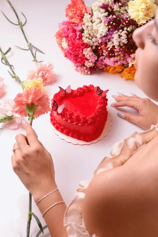 the woman is decorating the red cake on the table