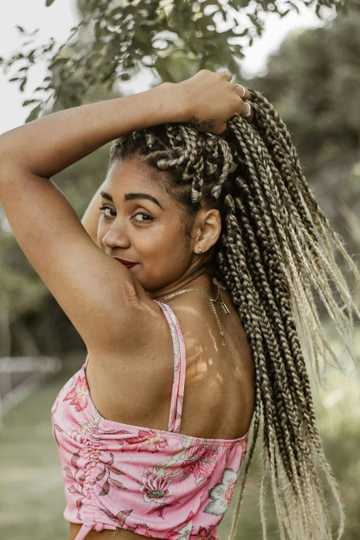 a woman in a pink top with lots of dreadlocks on her head