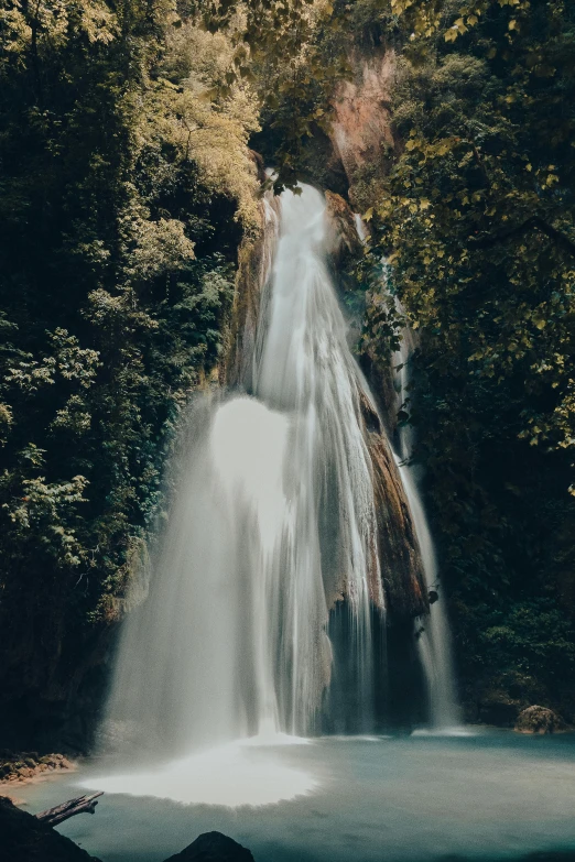 a waterfall surrounded by a bunch of green trees