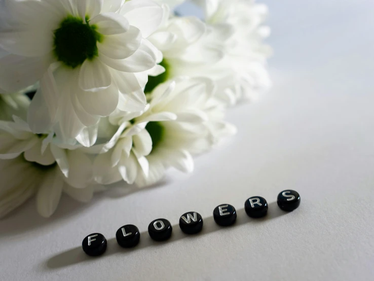 a white flower and black letters spelling flowers