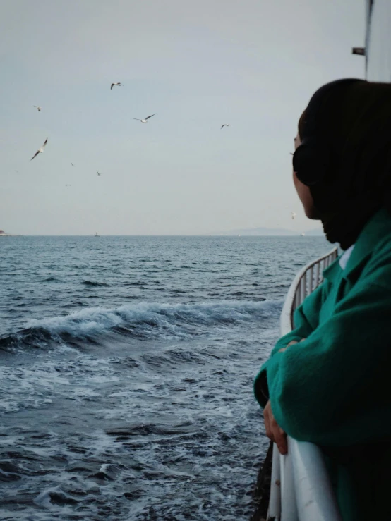 a woman standing on the back of a boat looking out at the ocean