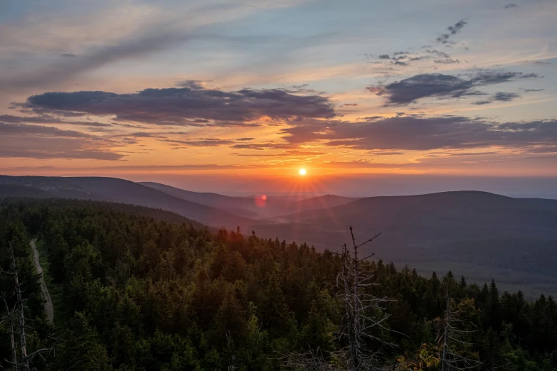 the sun rising over the mountains in the distance