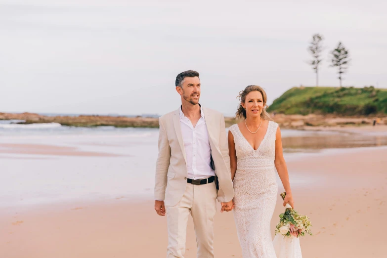 a man and woman walking on a beach holding hands