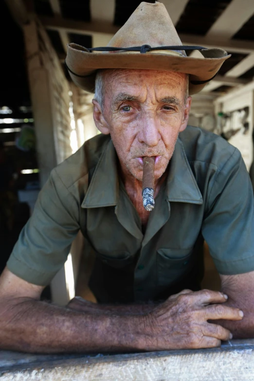 an old man smoking a cigarette in a cowboy hat