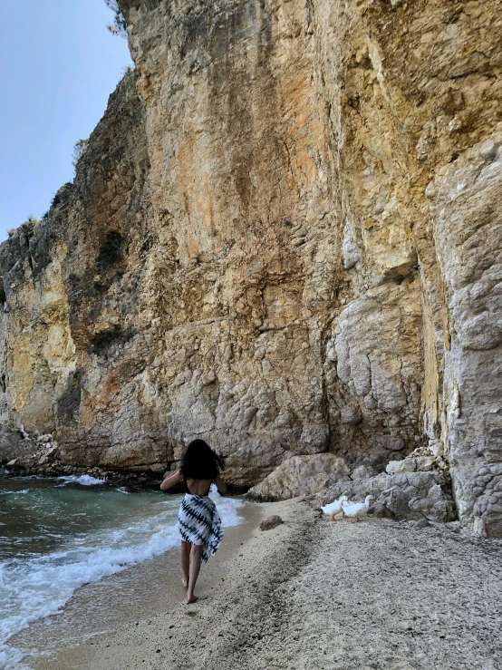 a person walking on the sand near a body of water