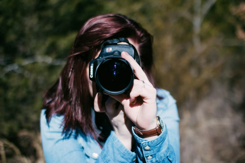 a woman in denim shirt taking po with camera