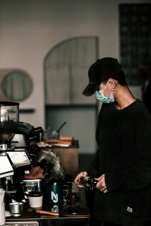 a lady wearing a mask and using a coffee maker