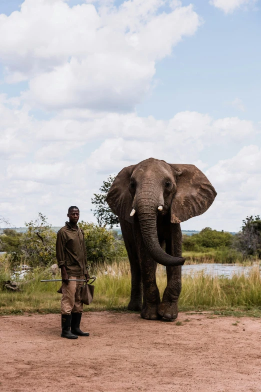 a man standing in front of an elephant on a dirt road