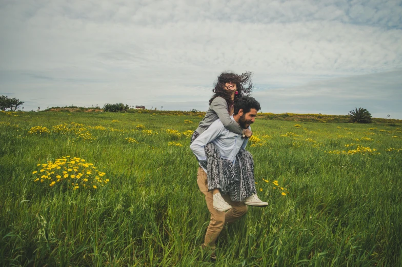 there is a man carrying a woman through the grass