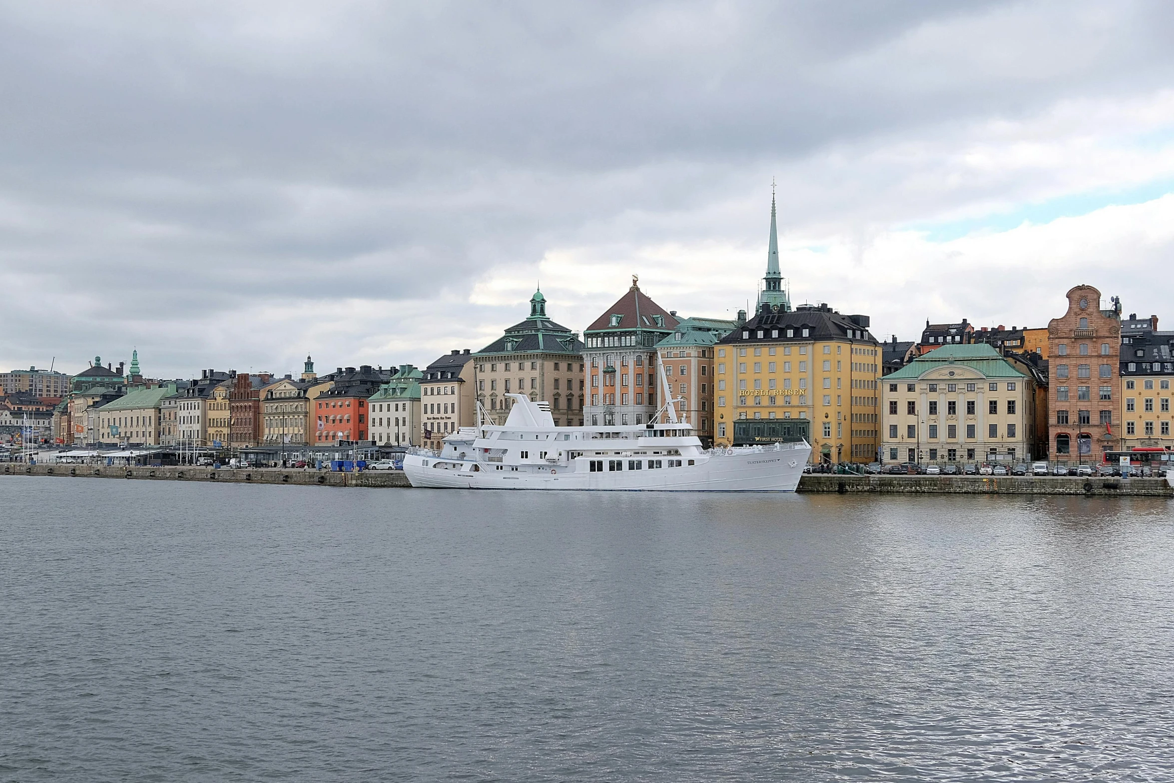 a large white boat in a bay next to buildings