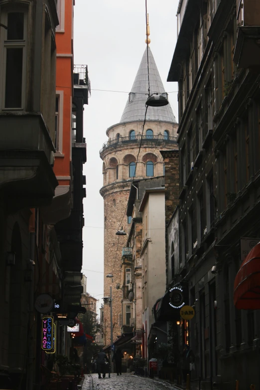a narrow street with a clock tower behind it