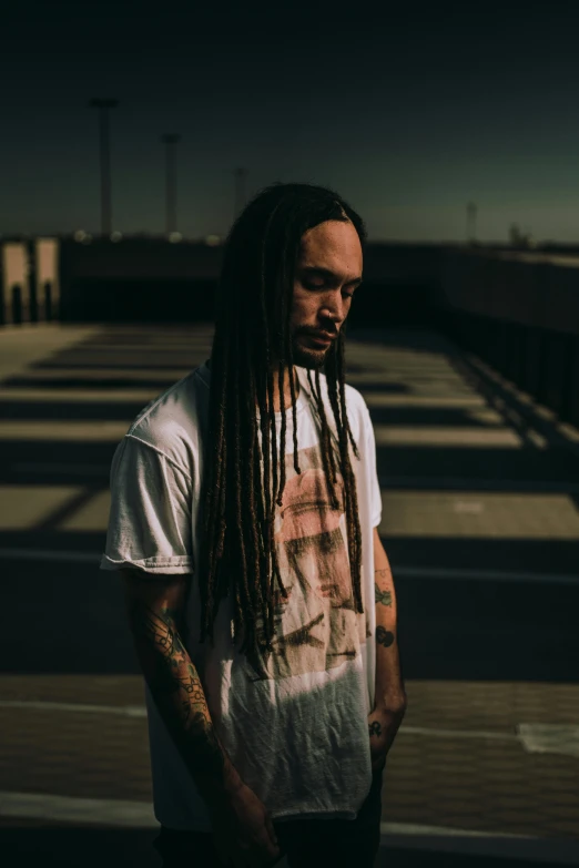 a man with a tattooed arm standing on a bridge