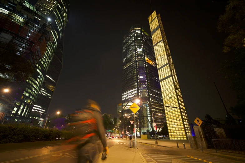 a person riding their bike at night near tall buildings