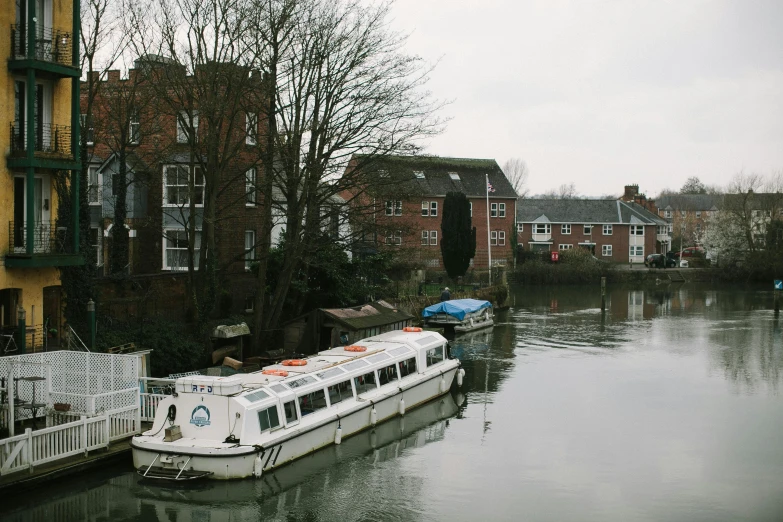 two white houseboats on the side of a river in town