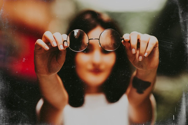 a woman holding up a pair of glasses to look through