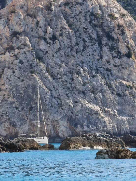 a boat in the ocean next to a rocky mountain