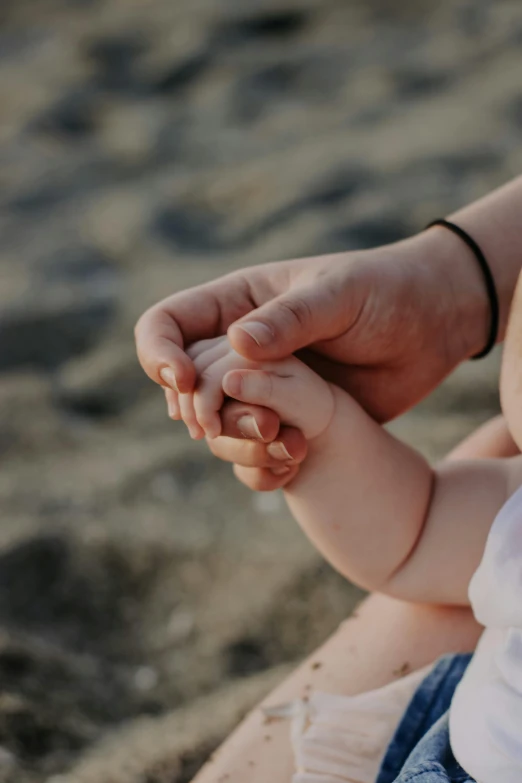 a close up of a hand holding the fingers of a child