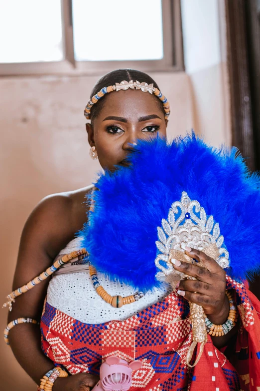 a woman holding up a blue feather fan