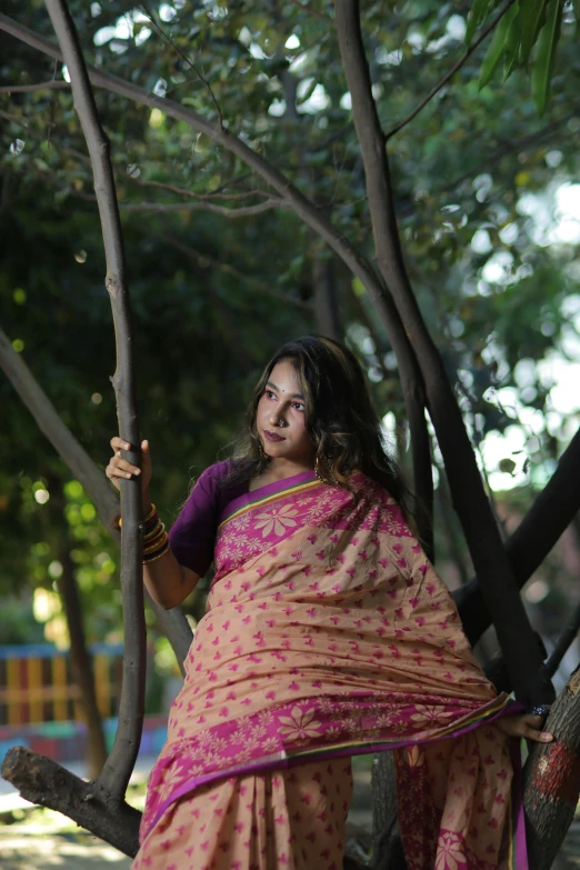 a woman sitting in a tree wearing a colorful dress