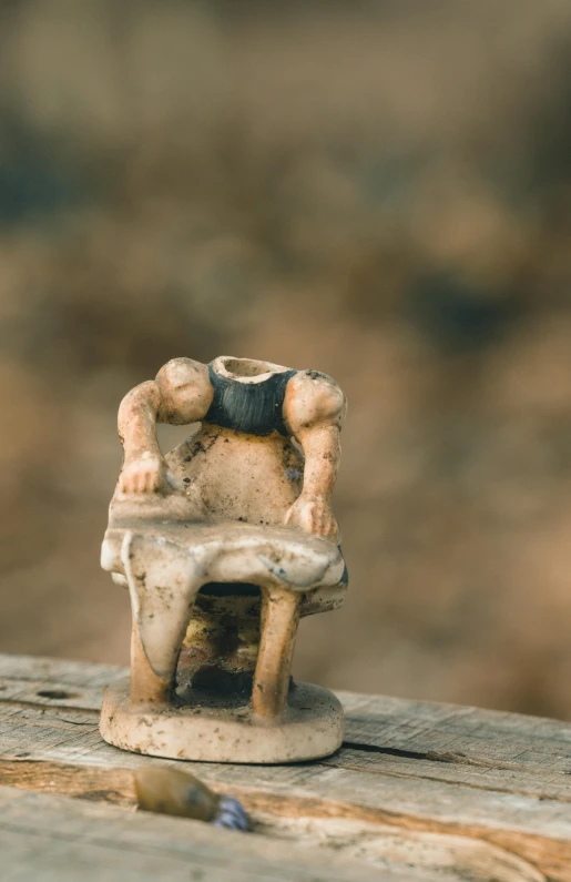 small toy boy in chair with arms outstretched on top of table