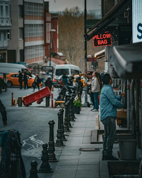 a woman stands near a row of restaurants and a street sign on the sidewalk