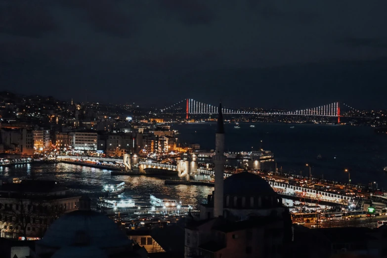 a large city lit up at night with a bridge in the background