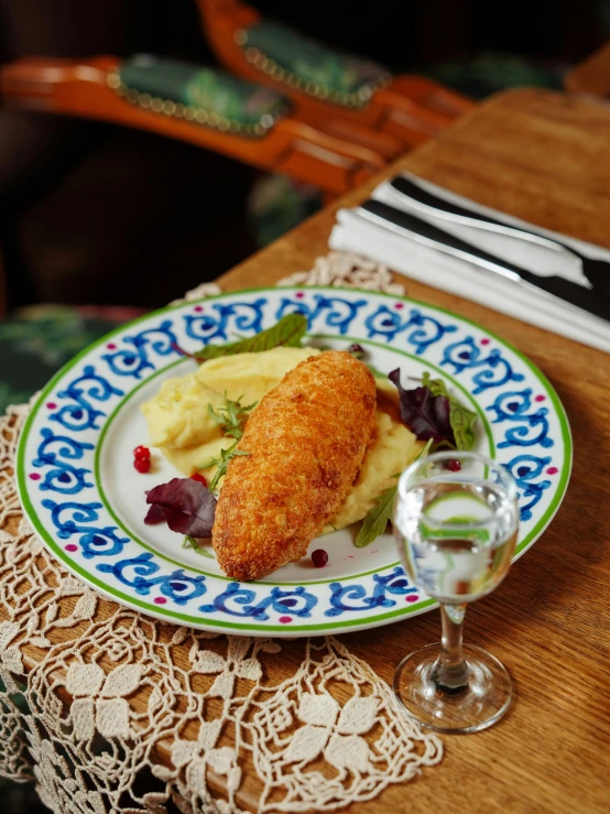 a plate on a table with food and wine glass