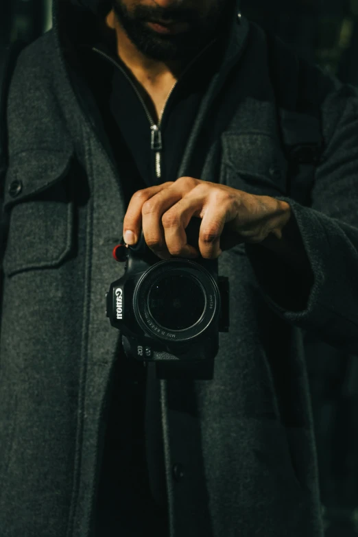 a man holding onto a black camera with his thumb on the lens