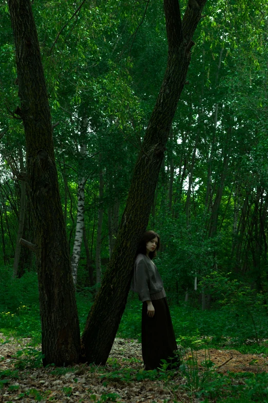 woman standing under a large tree in a forest