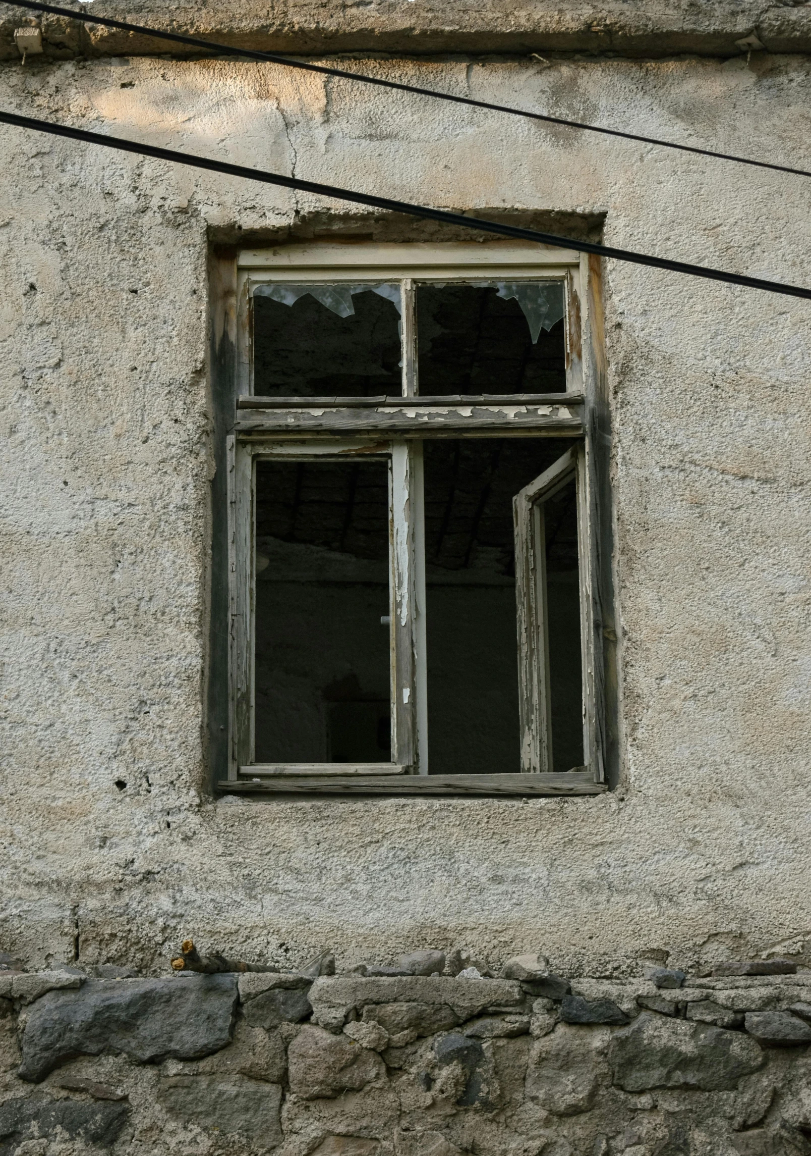 an old worn up building with a window and stone exterior