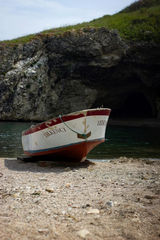 a boat is on the beach at a cliff