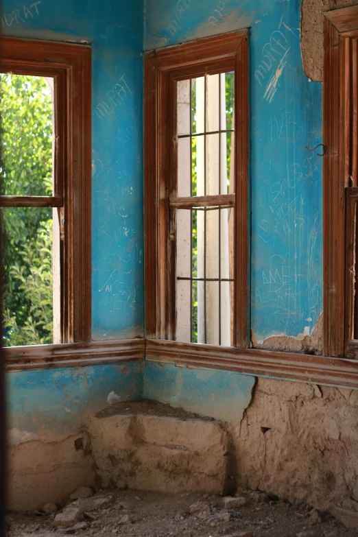 a blue room with three windows and no curtains