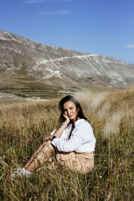 a beautiful young woman sitting in the grass