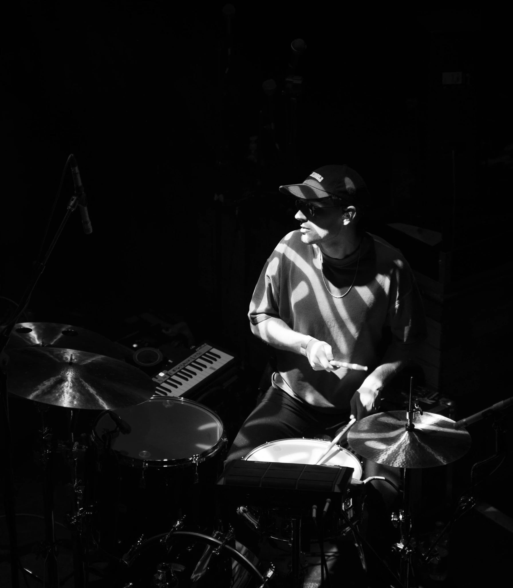 man in the dark playing his instruments while looking at a keyboard