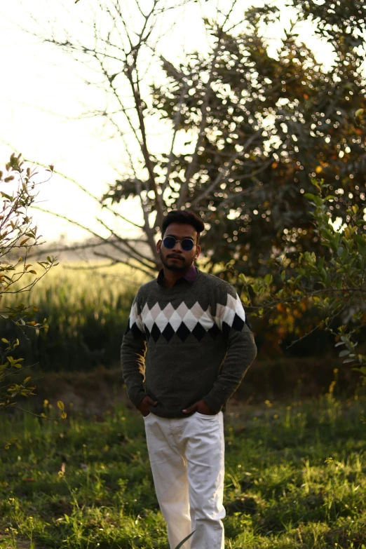 a man stands in a field and wears a sweater
