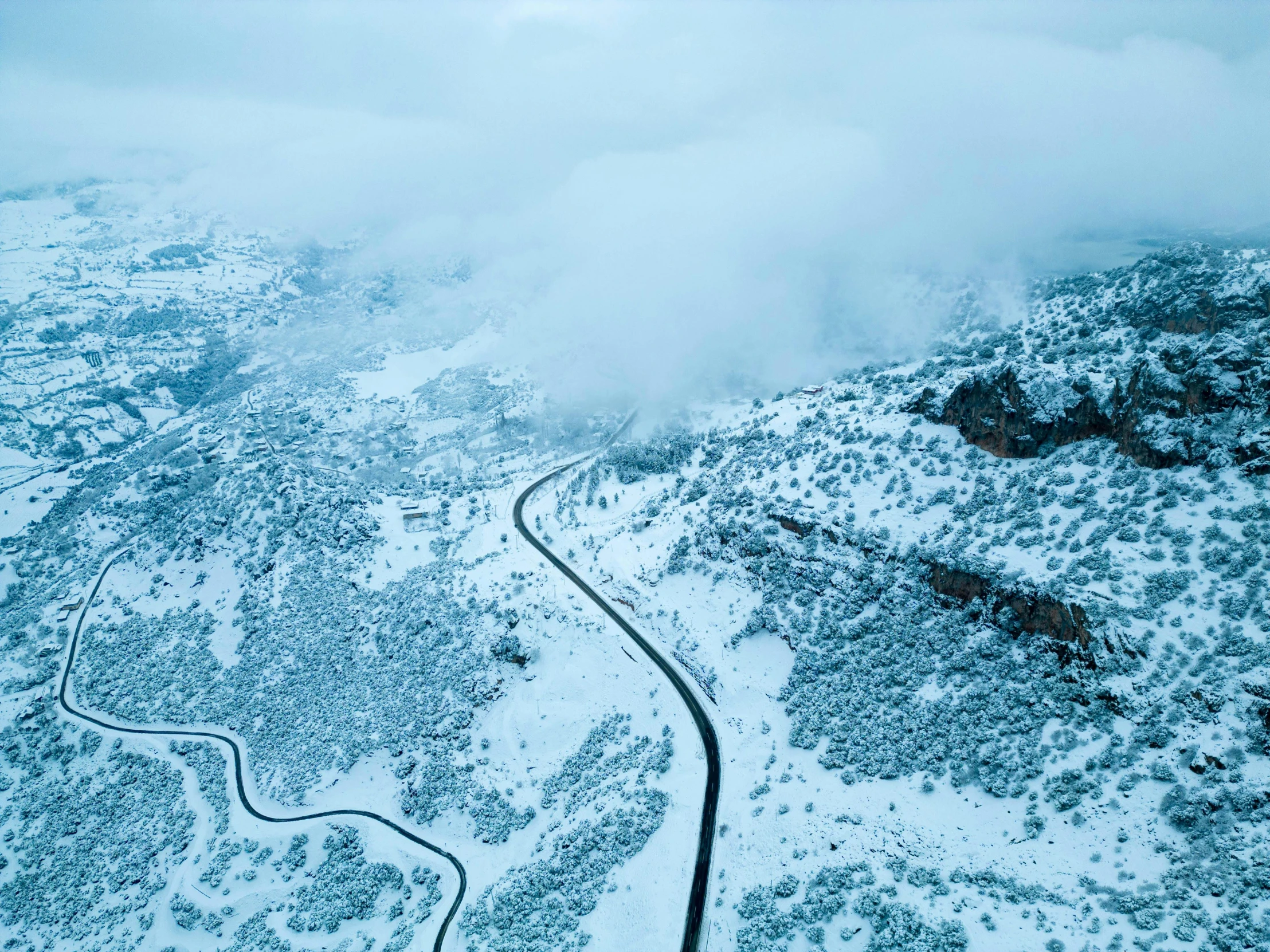 snowy scene with mountain and road curved in to it