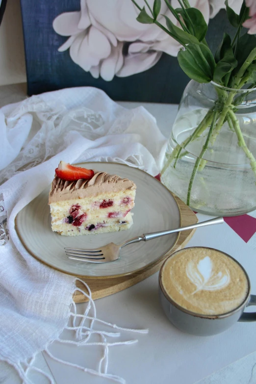 the piece of cake is placed on a plate next to the cappuccino and a glass of cappuccino coffee