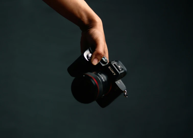 person holding onto camera with one hand and a camera