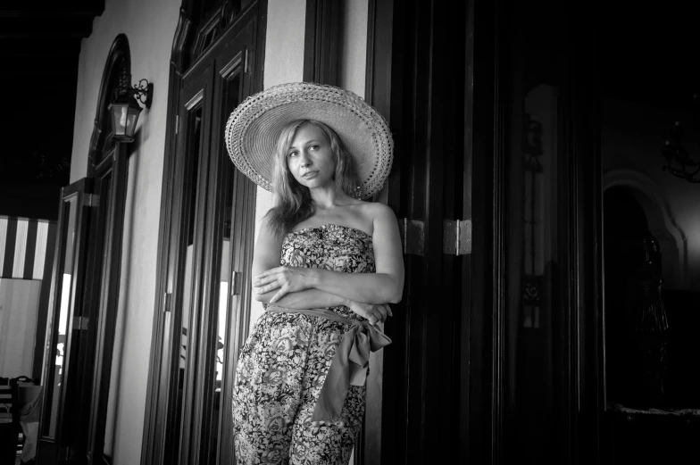 a woman in a hat standing by an open door