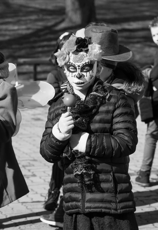 a woman standing on a sidewalk wearing a carnival mask