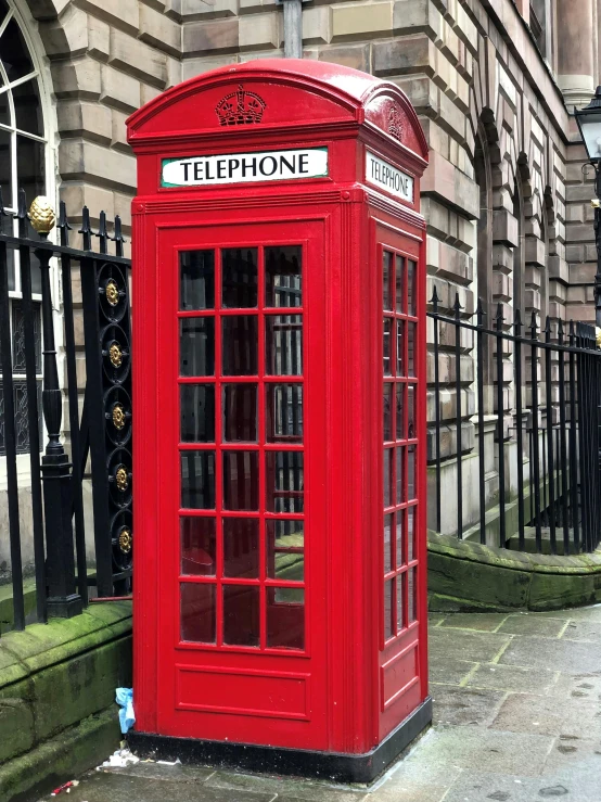 a red phone booth sitting by the side of the street